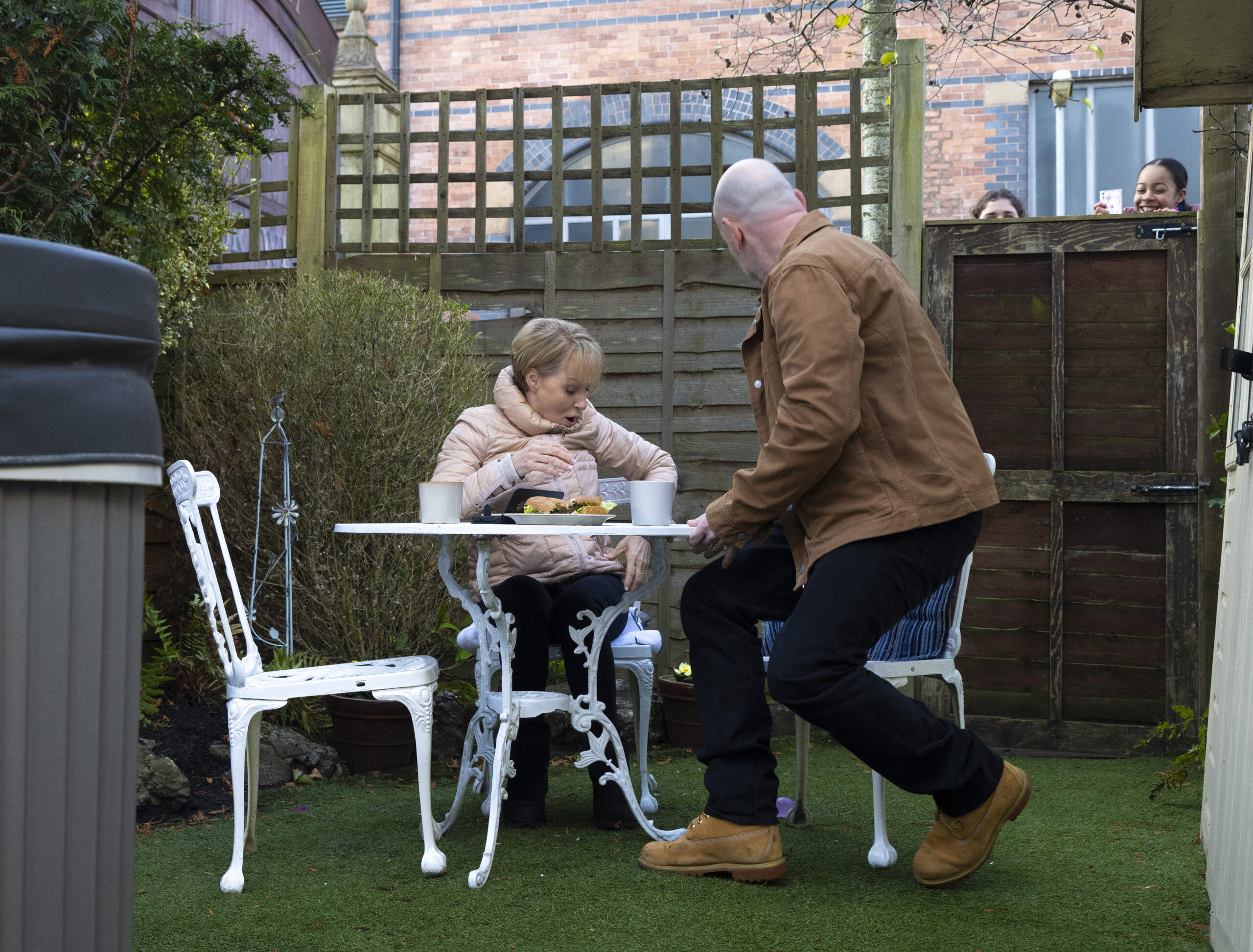 Hope and Ruby peering over fence at Sally and Tim