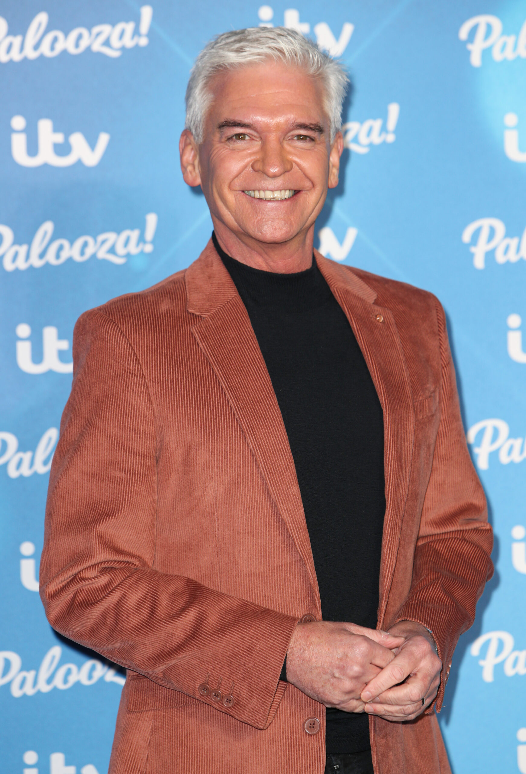 Phillip Schofield smiling in a brown jacket