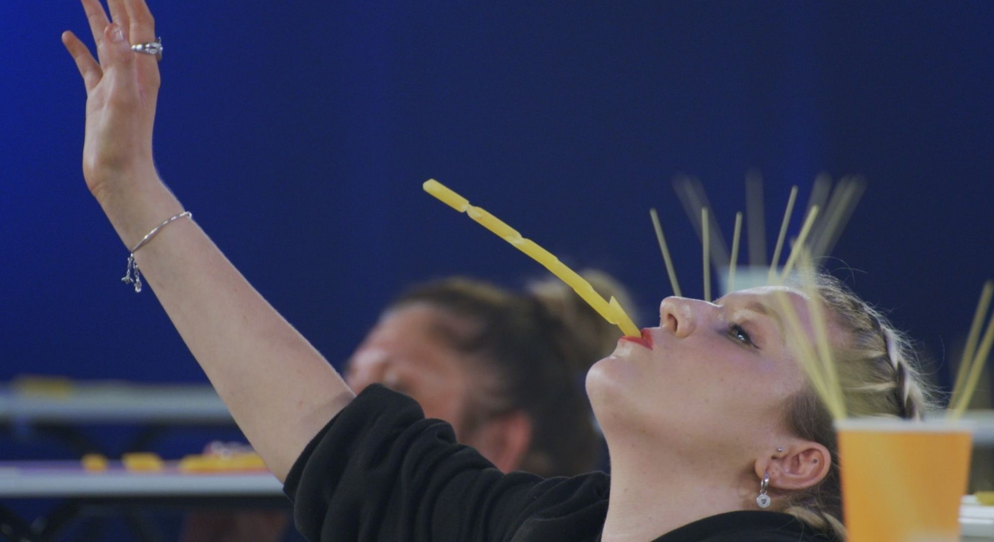 A woman putting pasta on spaghetti using her mouth