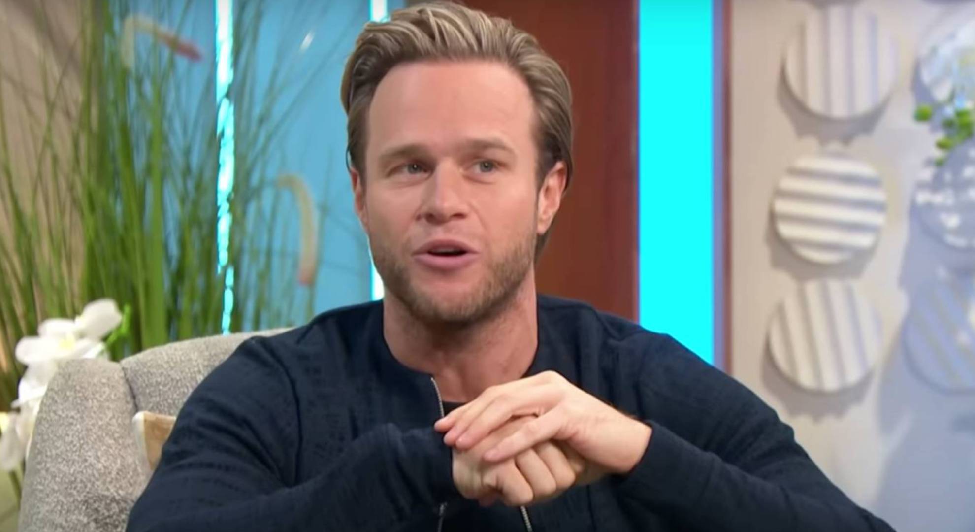 Olly Murs looks to his side and folds his hands