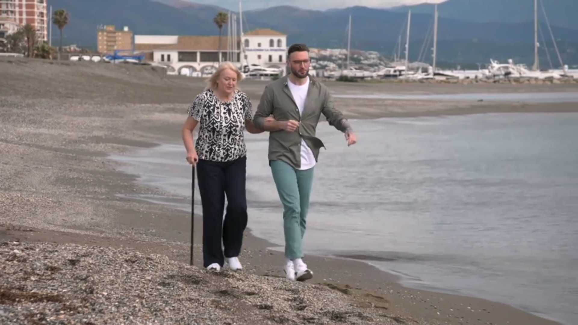 A couple on the beach with the woman using a walking stick