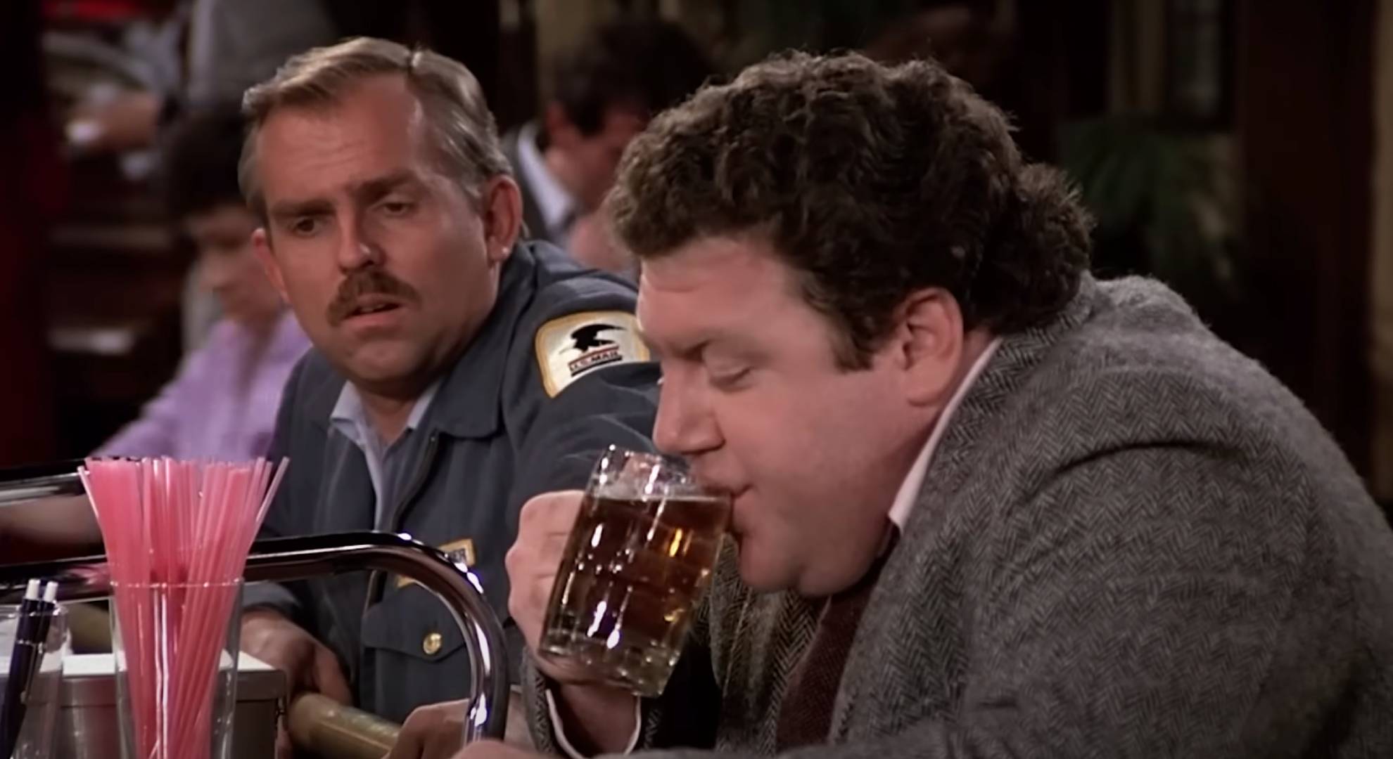 George Wendt takes a sip of beer in character as Norm in Cheers