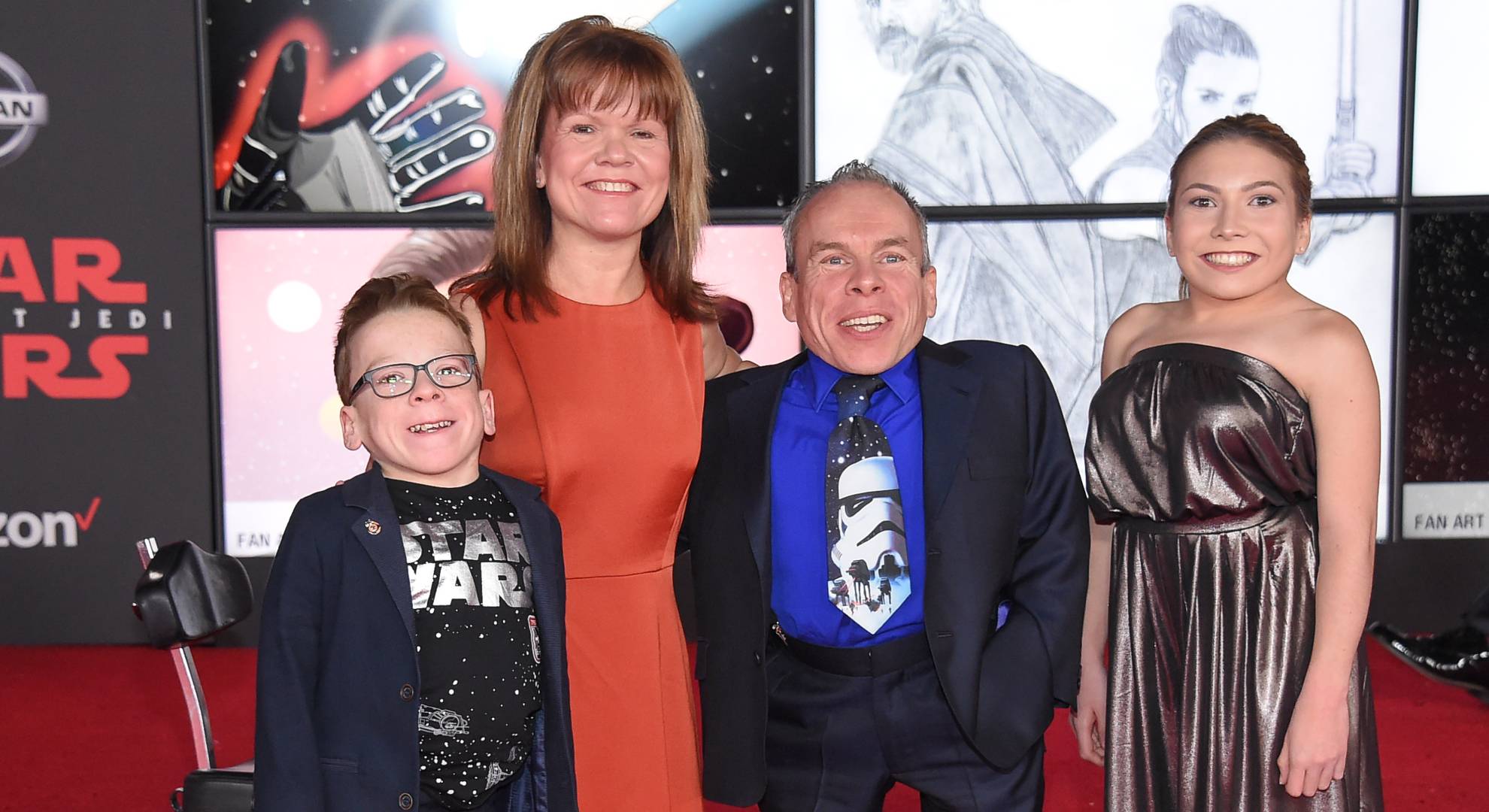 Warwick Davis smiles alongside his family