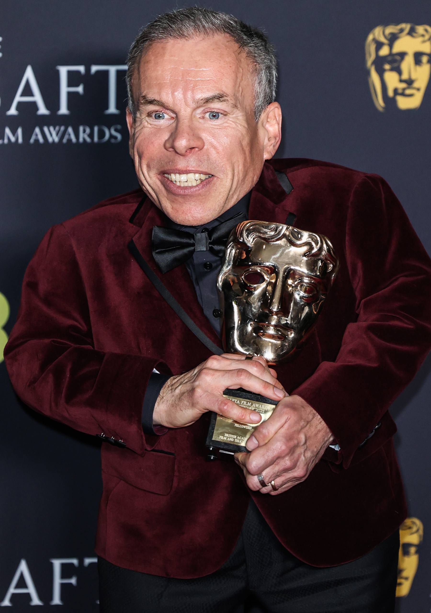 Warwick Davis holding an award