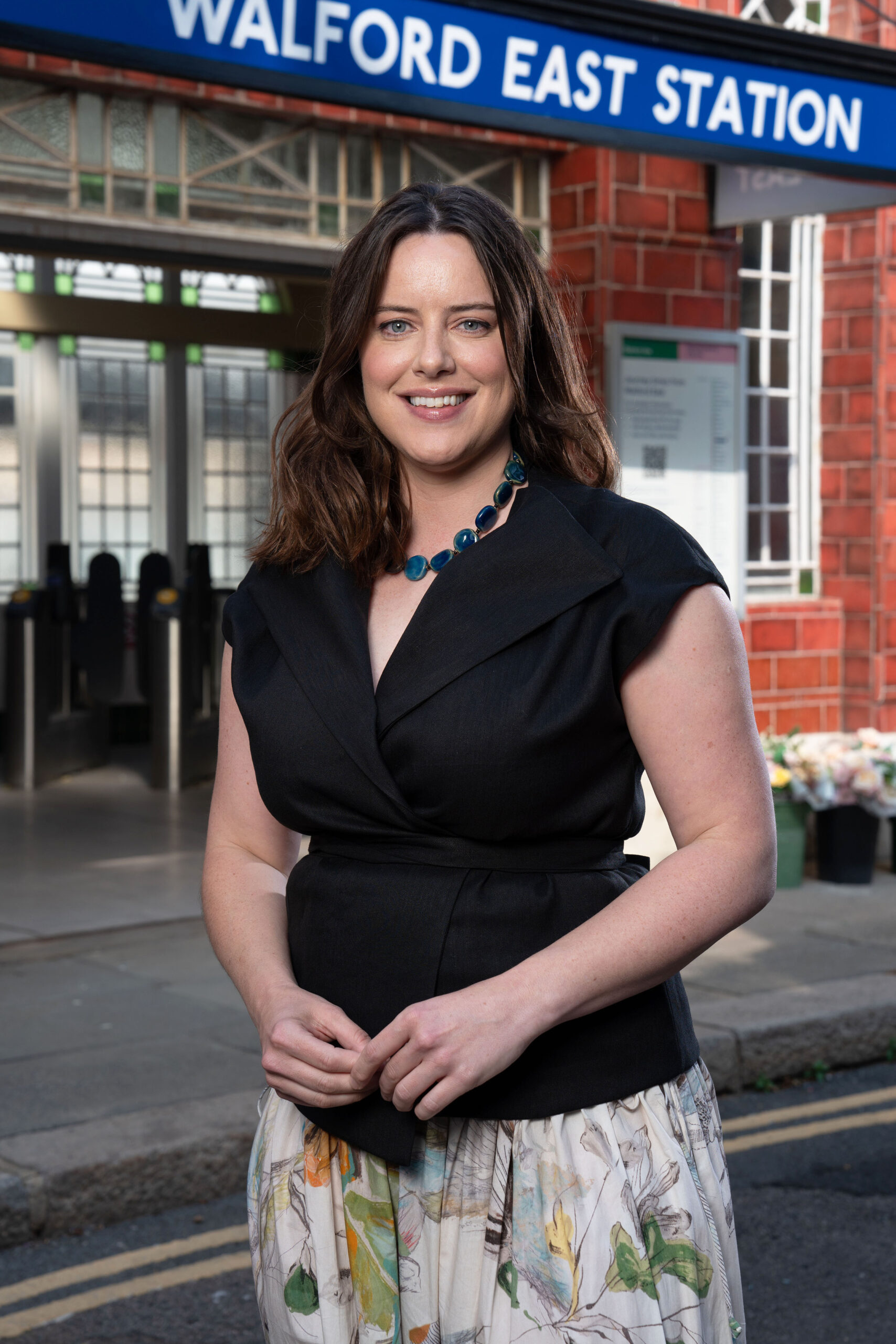 Michelle Ryan as Zoe Slater, smiling in front of Walford tube