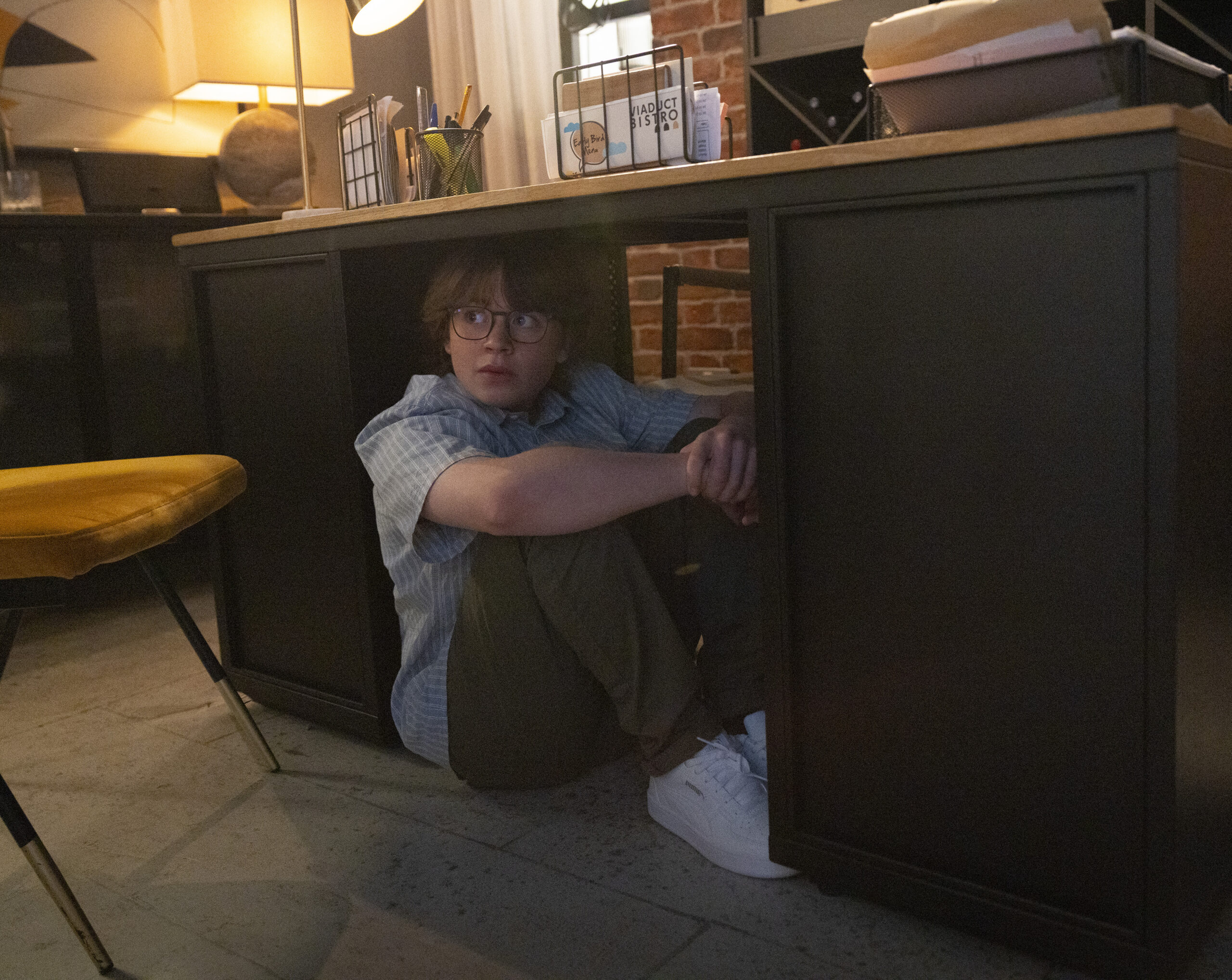 Sam hiding under office desk