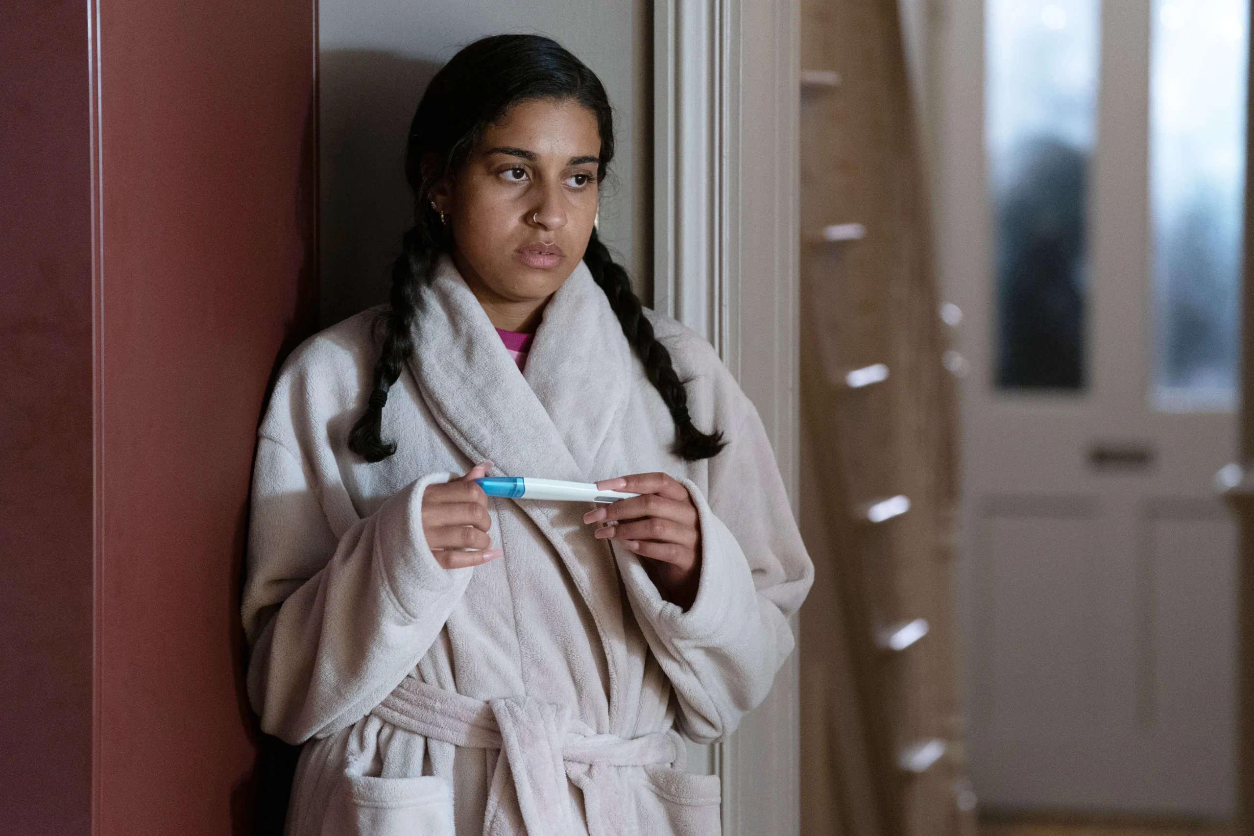 Avani looks worried as she holds a pregnancy test on EastEnders