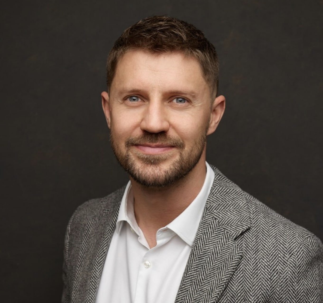 Adam Fadlé in a smart suit in front of a dark background