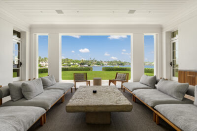Robbie Williams' living area featuring a table, grey couches, and a giant window.