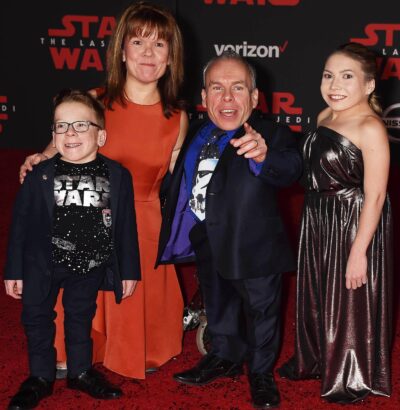 Warwick Davis points alongside his wife and family
