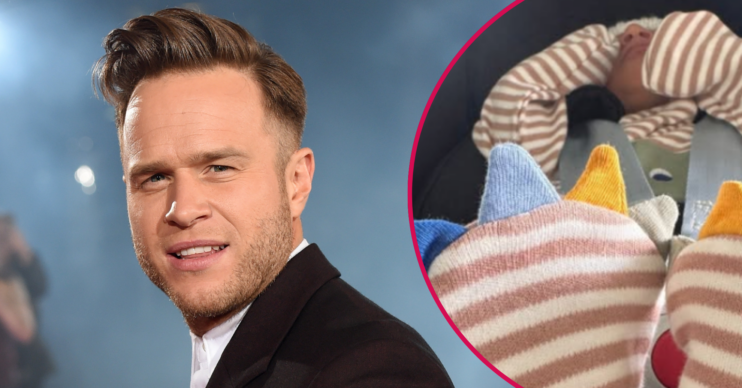 Olly Murs looking to camera and his new baby in a car seat