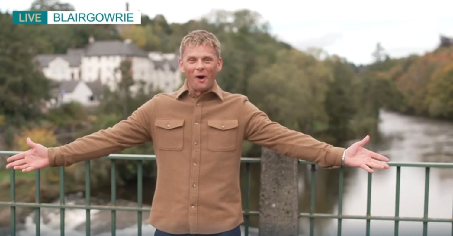 Jeff Brazier with his arms spread on a bridge