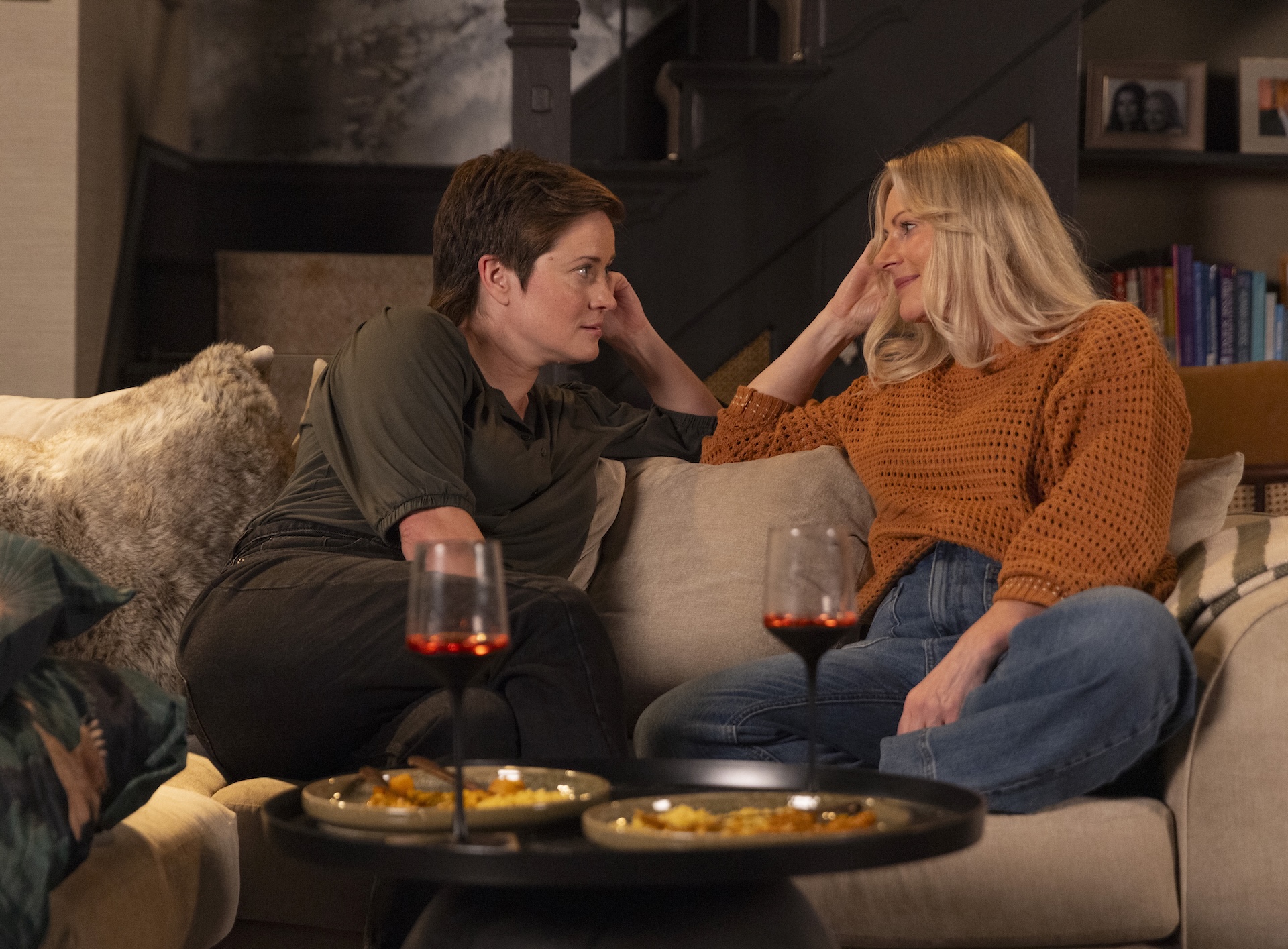 Becky and Lisa sit on the sofa close together 