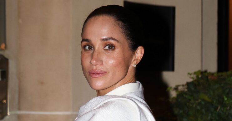 Meghan Markle smiling at the camera at Paris Fashion Week
