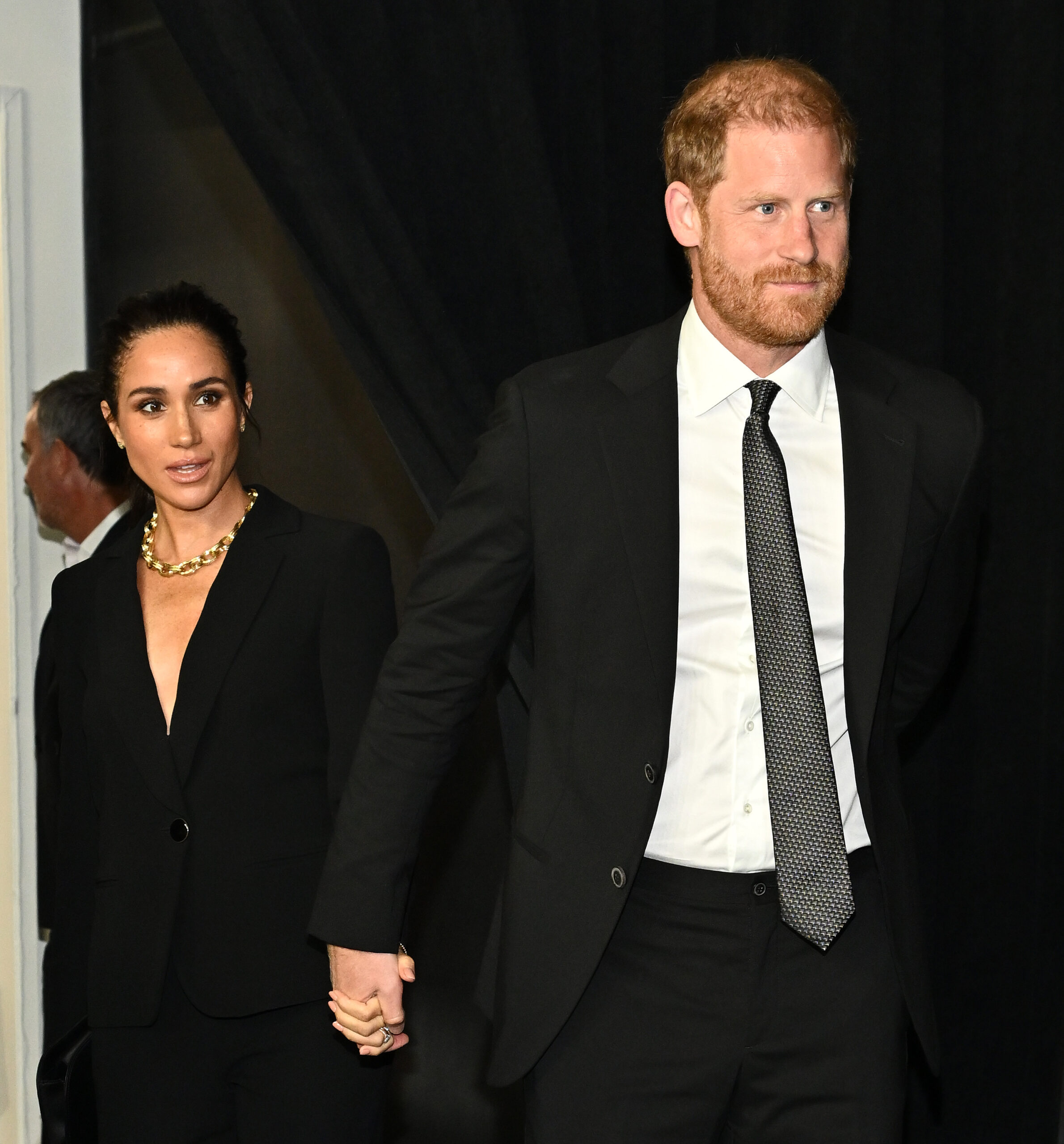 Meghan Markle walking hand-in-hand wearing black suits