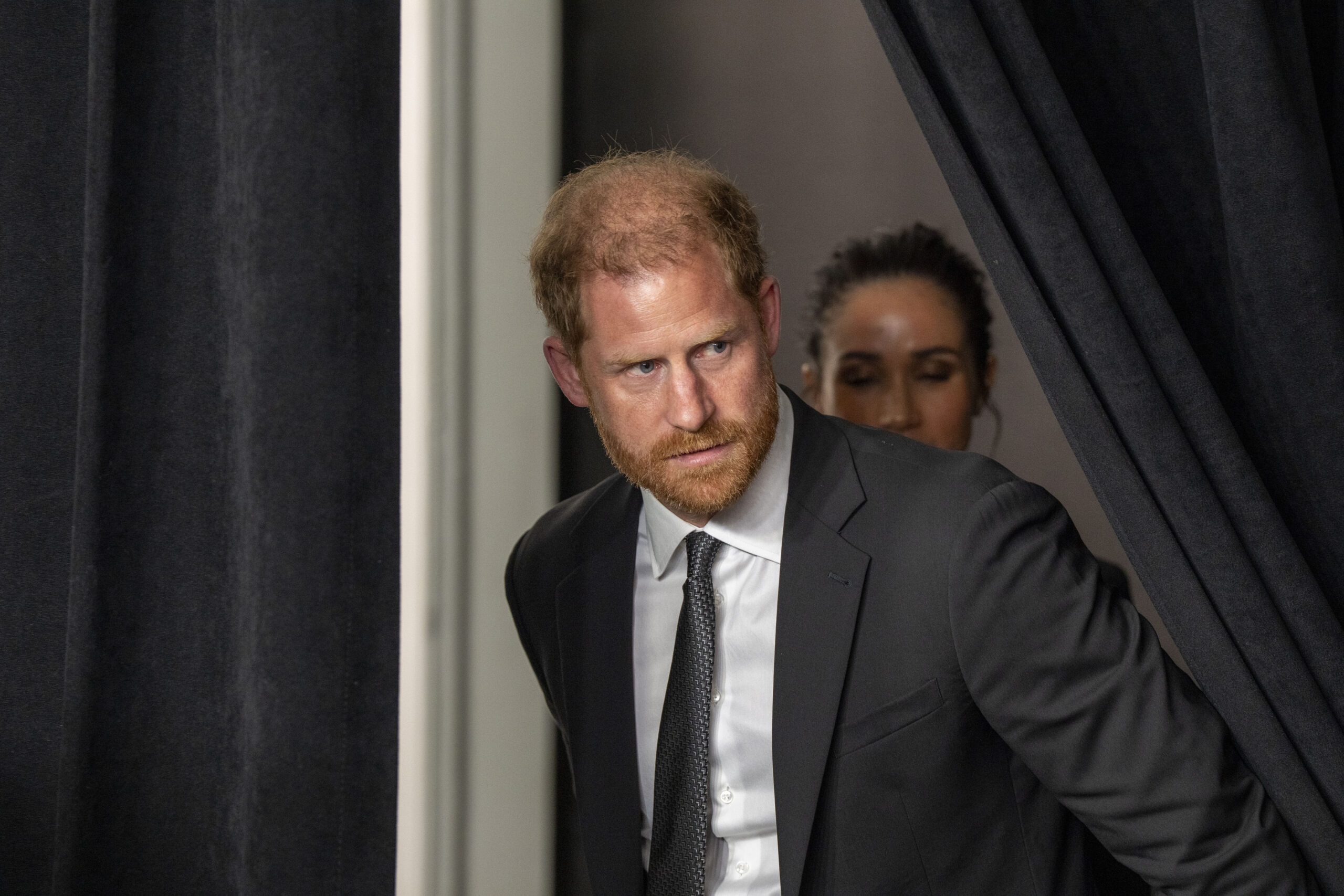 Prince Harry in New York with Meghan Markle behind him