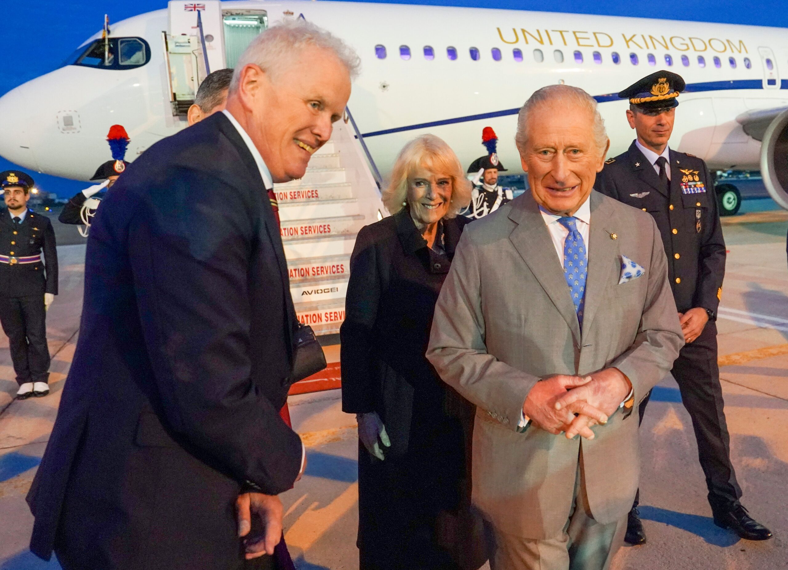 King Charles and Queen Camilla smiling as they step off an aircraft in Rome