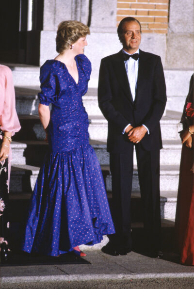 Princess Diana laughing and smiling as she looks at King Juan Carlos whilst she wears a long blue dress