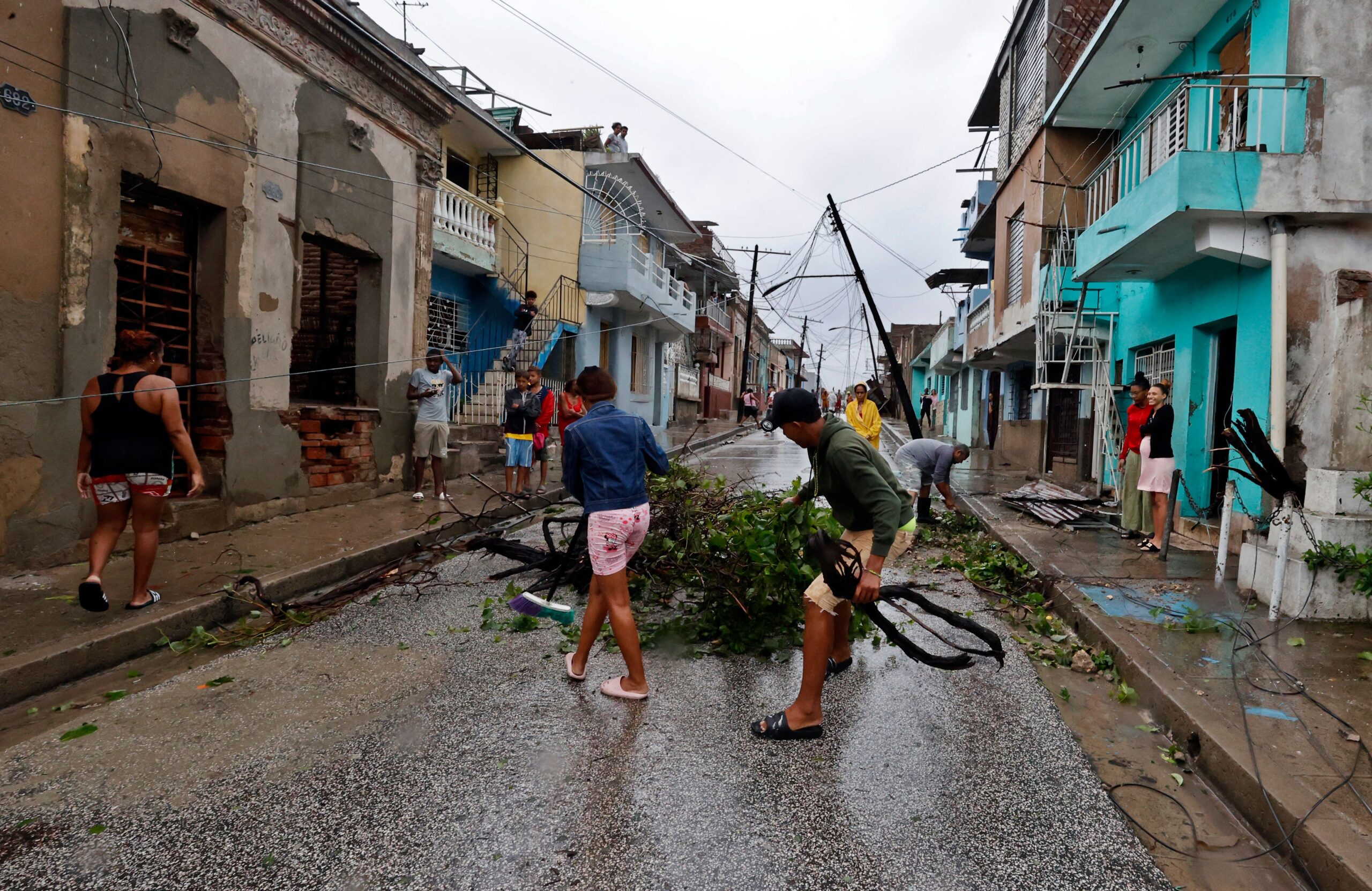 People clear debris on a street affected by Hurricane Melissa in Santiago de Cuba