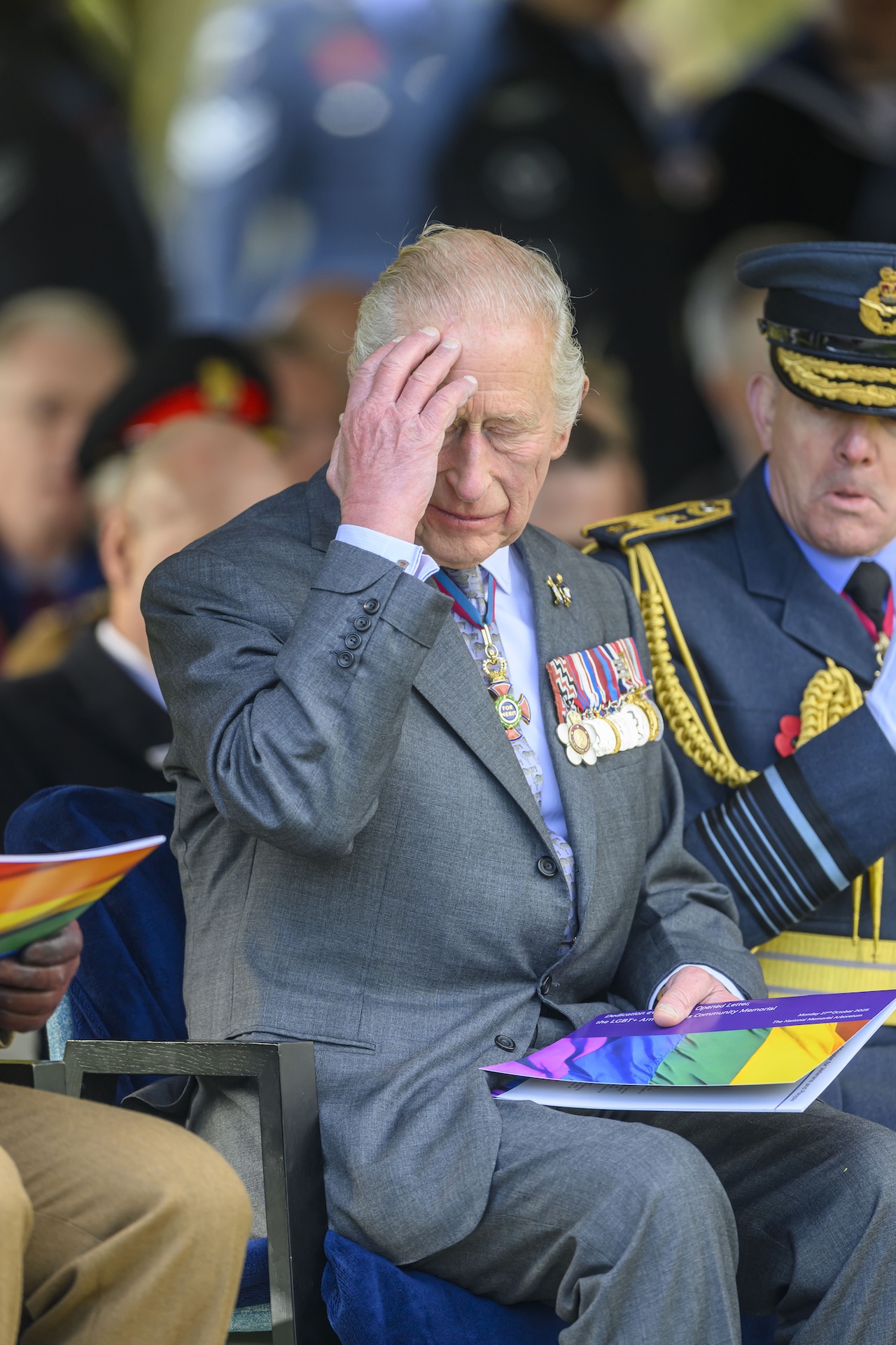 King Charles holding his head while at a royal event
