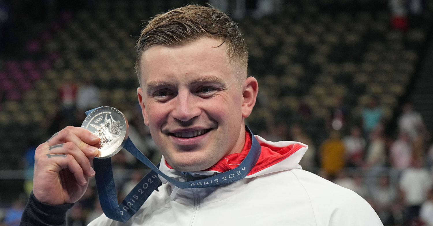 Adam Peaty holding up silver medal