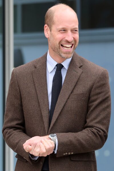 Prince William smiling and laughing in brown suit
