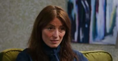 Davina McCall wears a blue blouse and sits on a green armchair