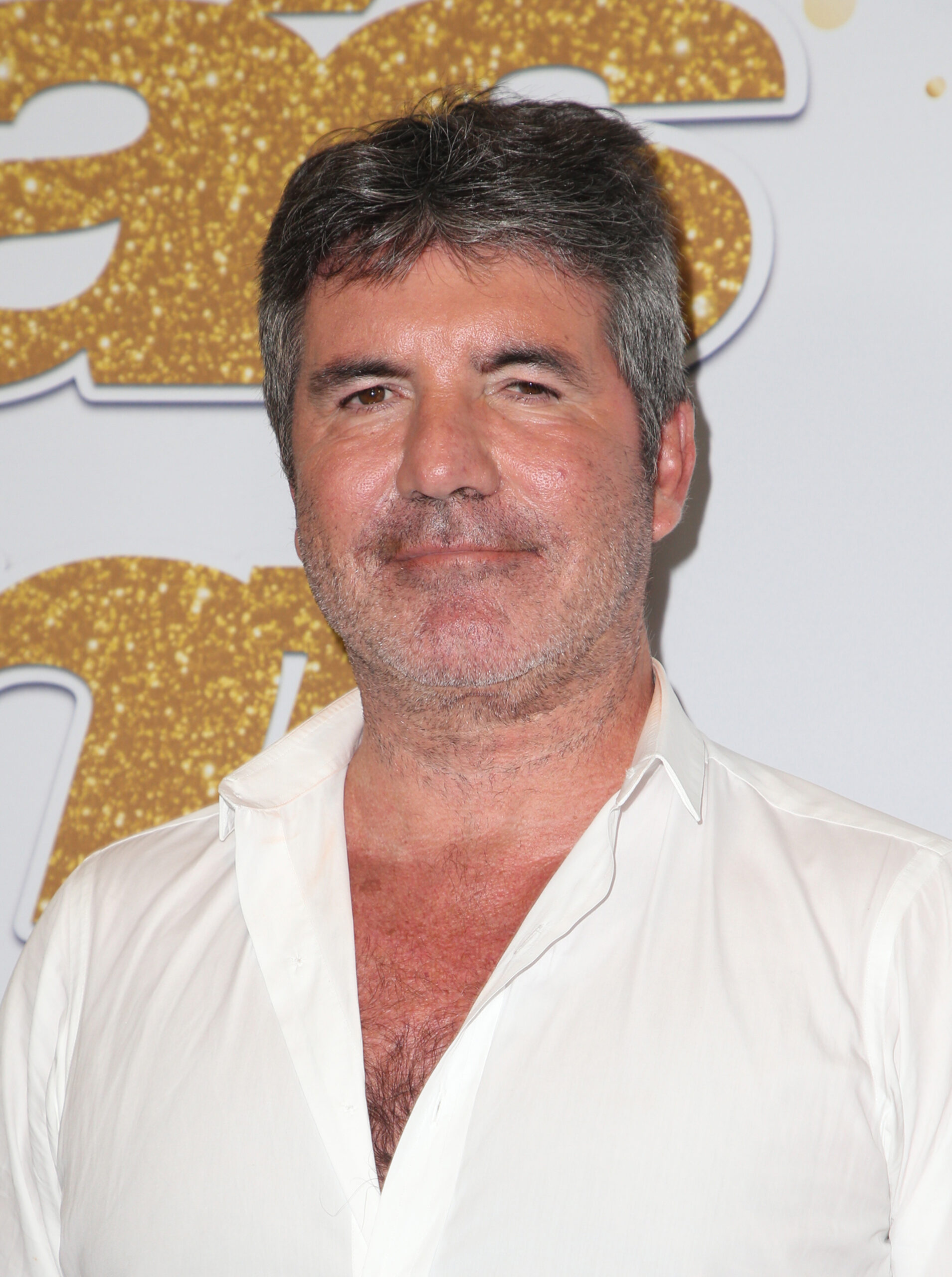 Simon Cowell wearing a white shirt looking fuller in the face
