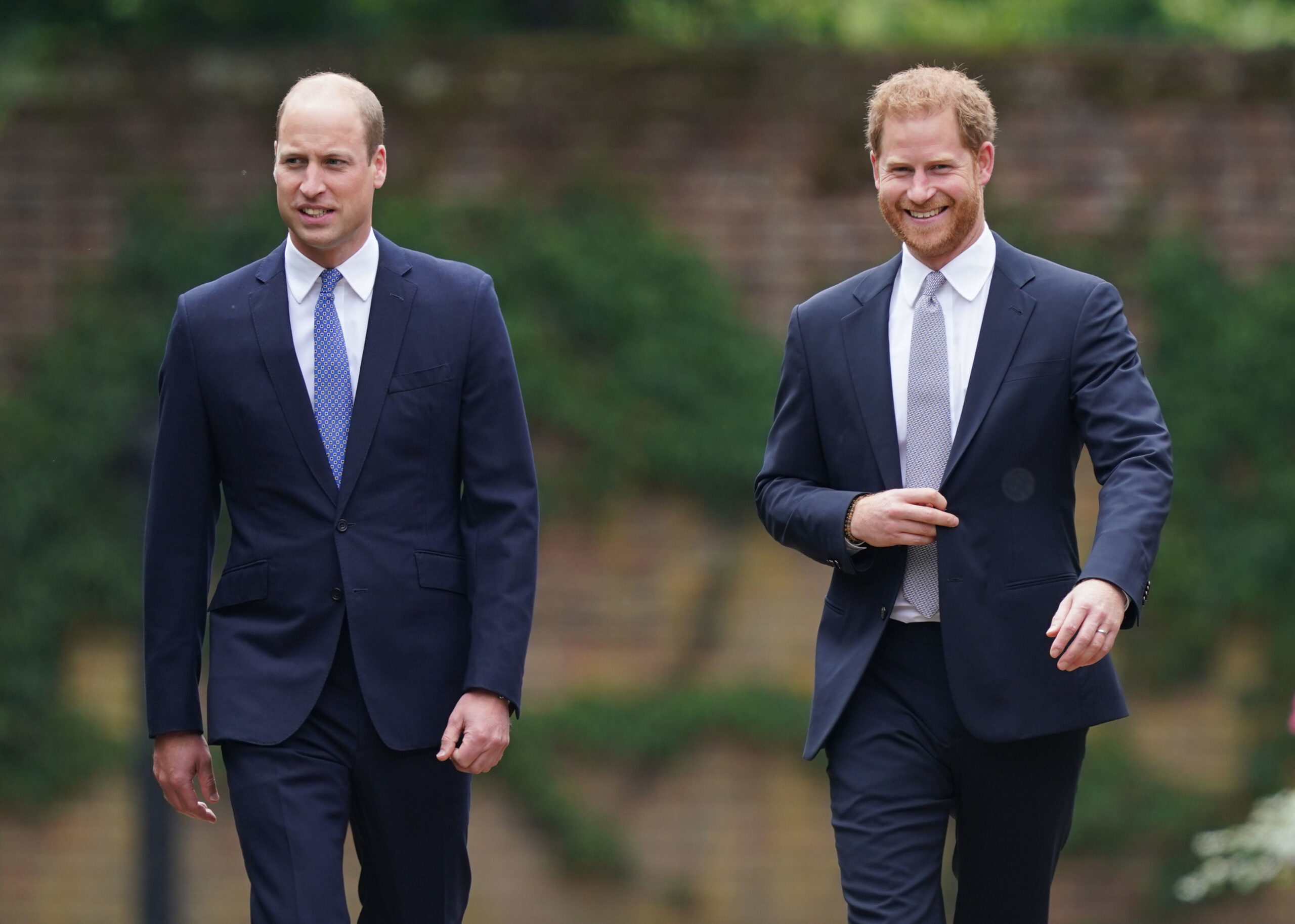 Prince William and Prince Harry walking next to each other and smiling