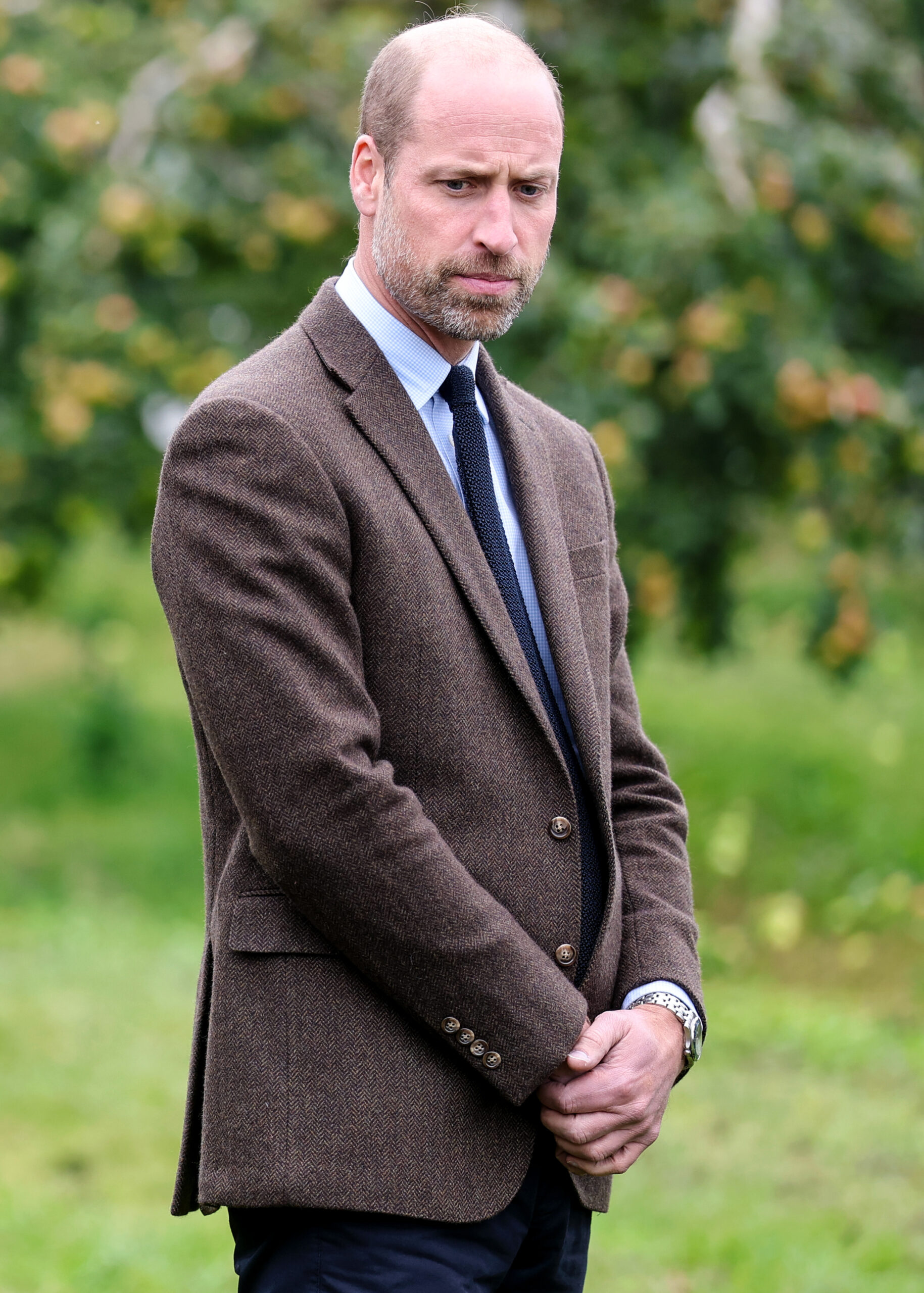 Prince William frowning an looking down with his hands clasped