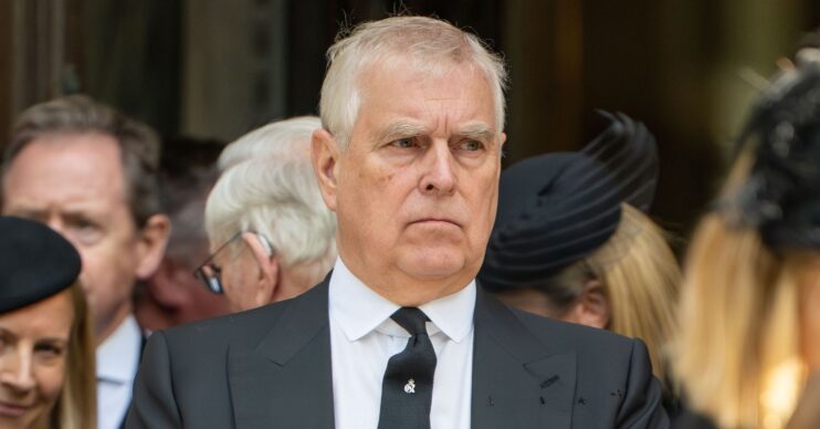 Andrew Mountbatten-Windsor frowning wearing a black suit and tie