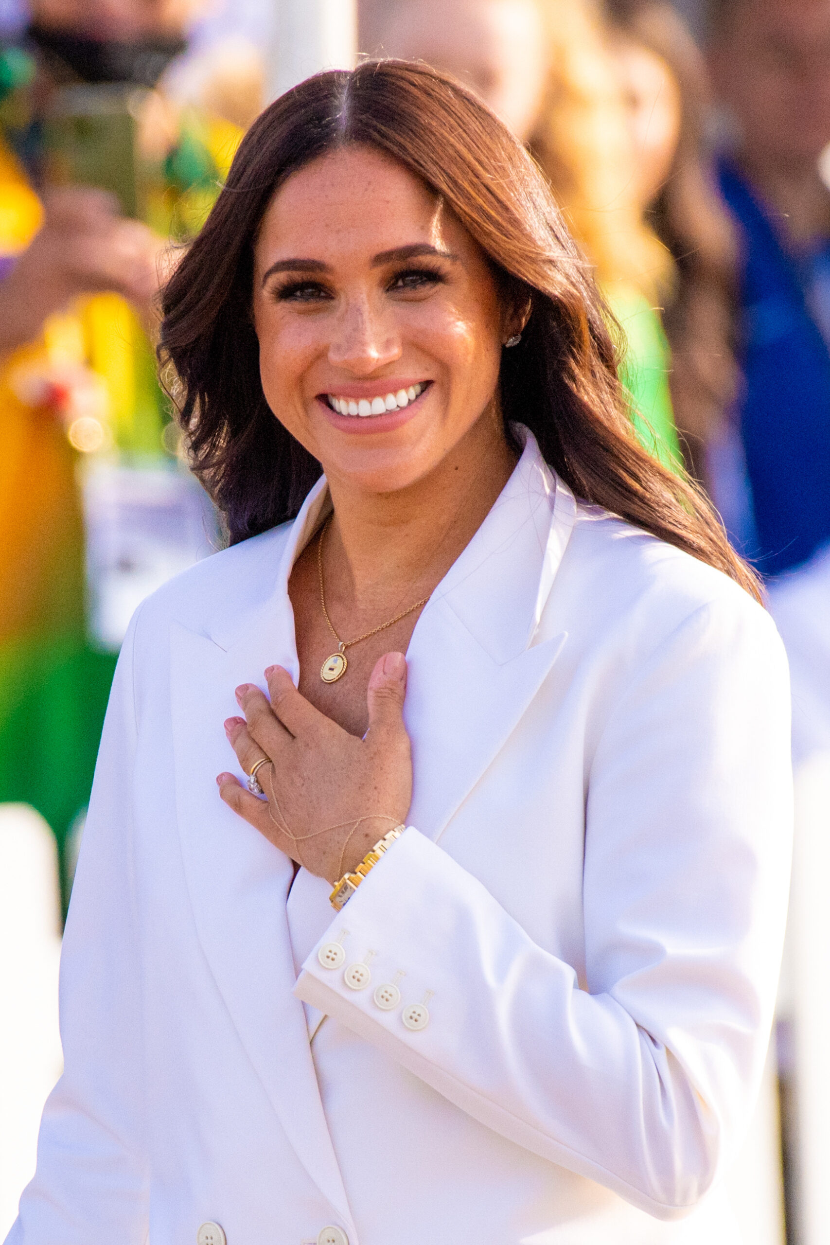 Meghan Markle smiling with her hand on her chest