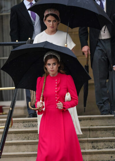 Princess Eugenie and Princess Beatrice walking down stairs holding umbrellas
