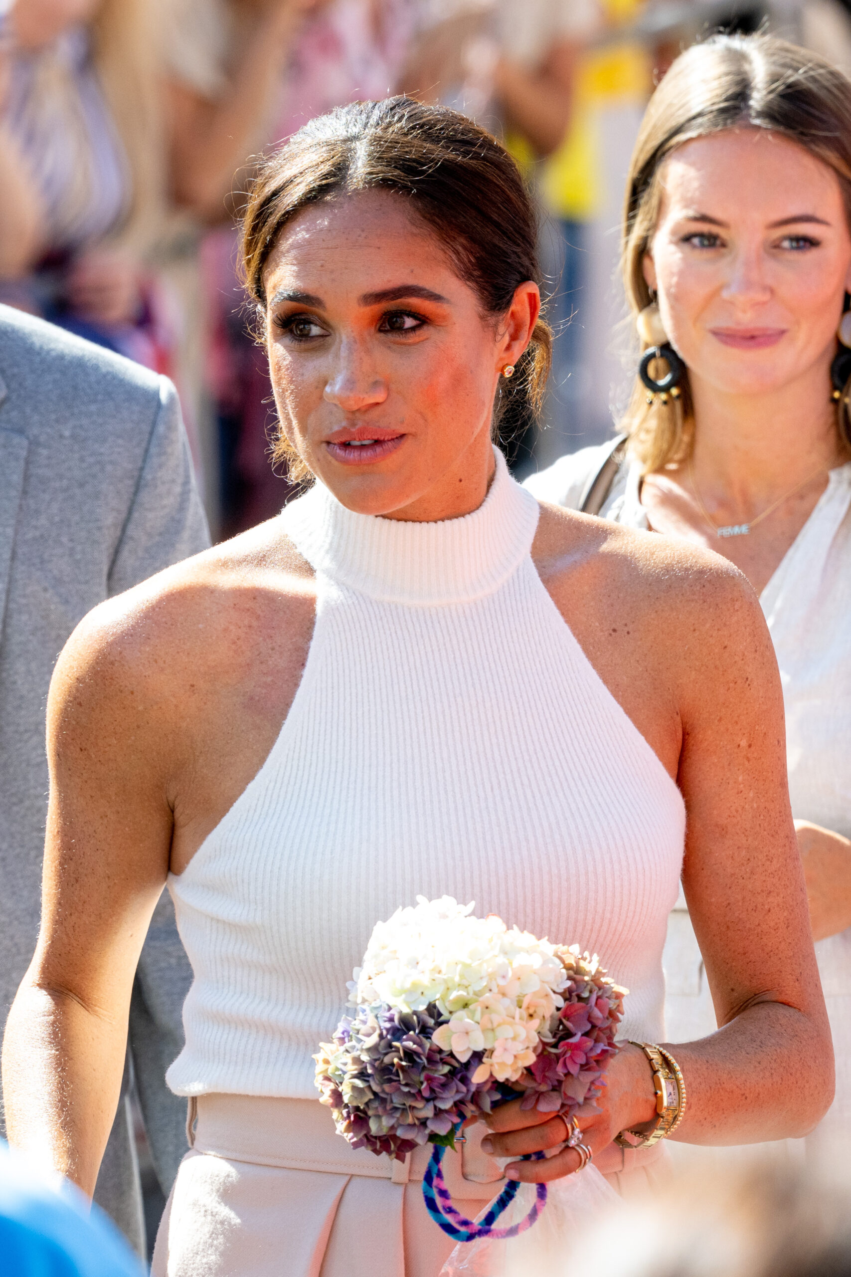Meghan Markle wearing white and holding flowers