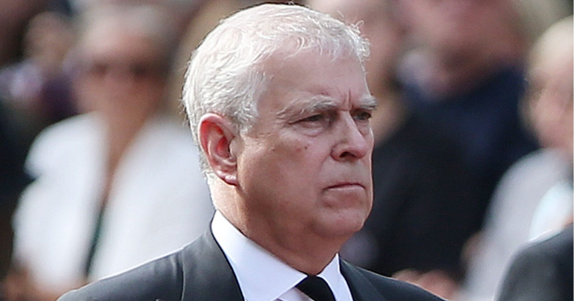 Andrew Mountbatten-Windsor frowning wearing a black suit