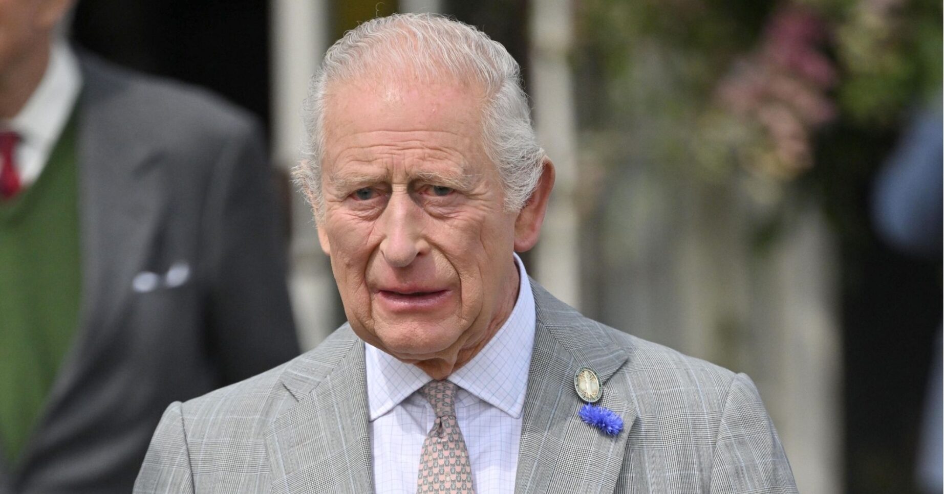 King Charles in grey suit looking worried