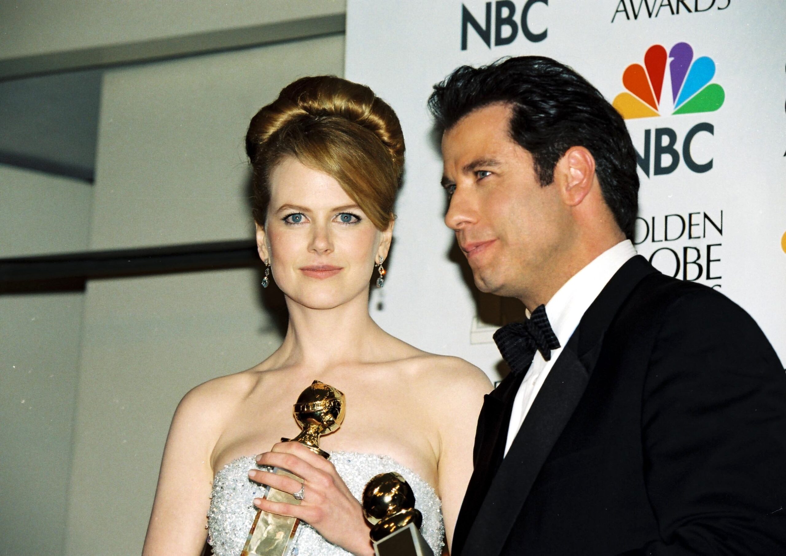 Nicole Kidman and John Travolta holding Golden Globe awards whilst posing together 