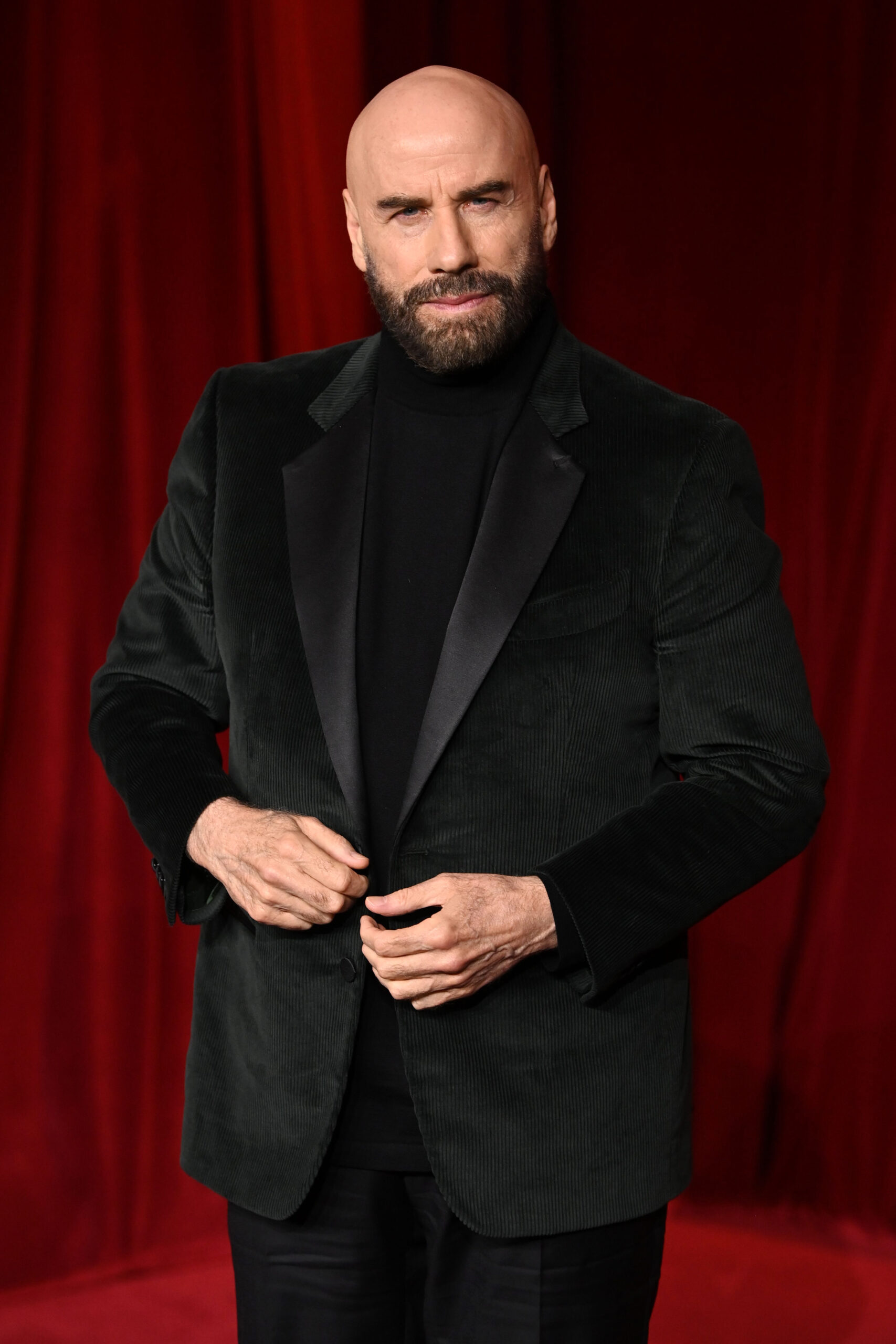 John Travolta posing wearing a velvet suit jacket