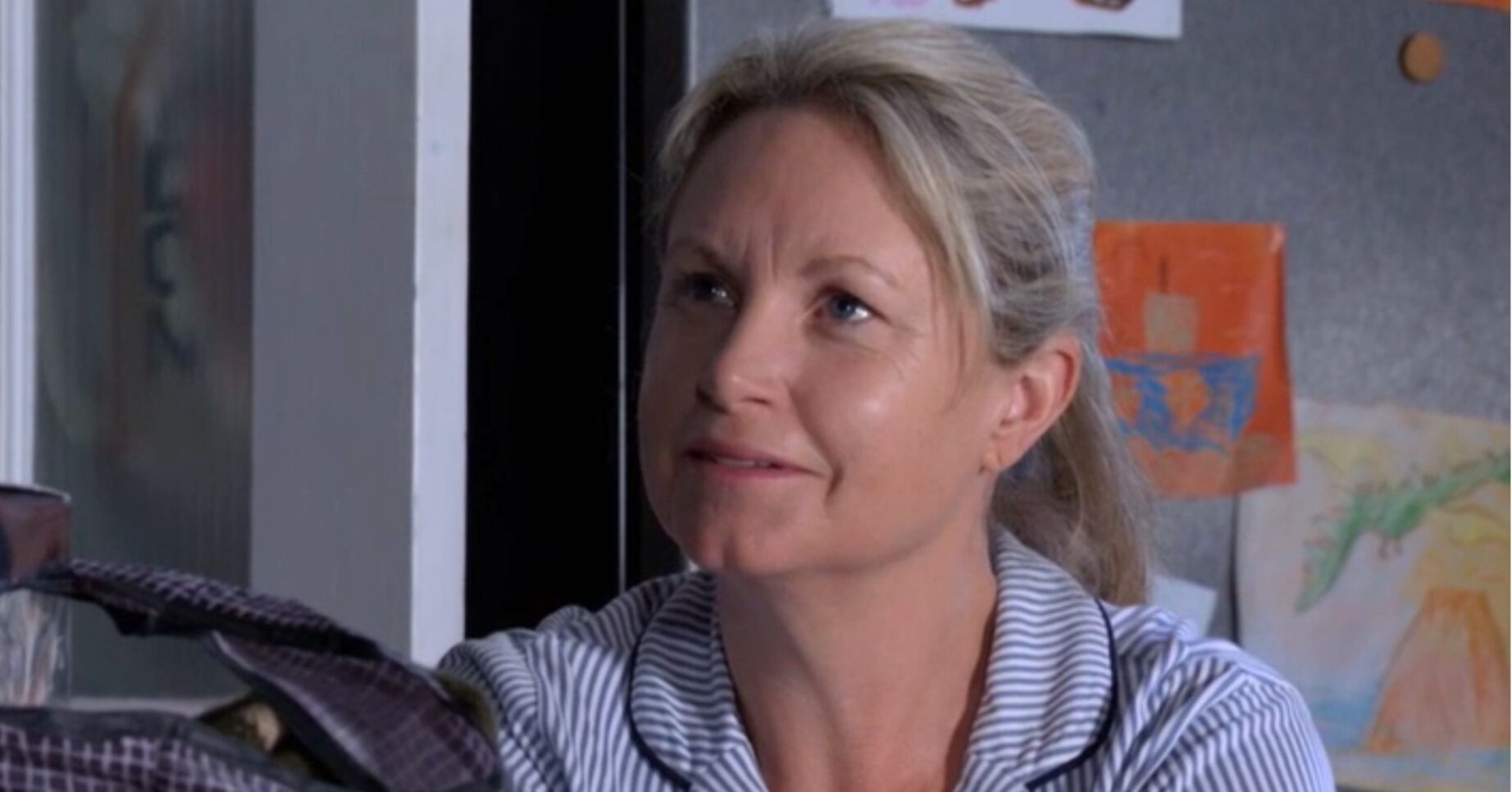 Sam looking up at Phil as they talk in the kitchen in EastEnders