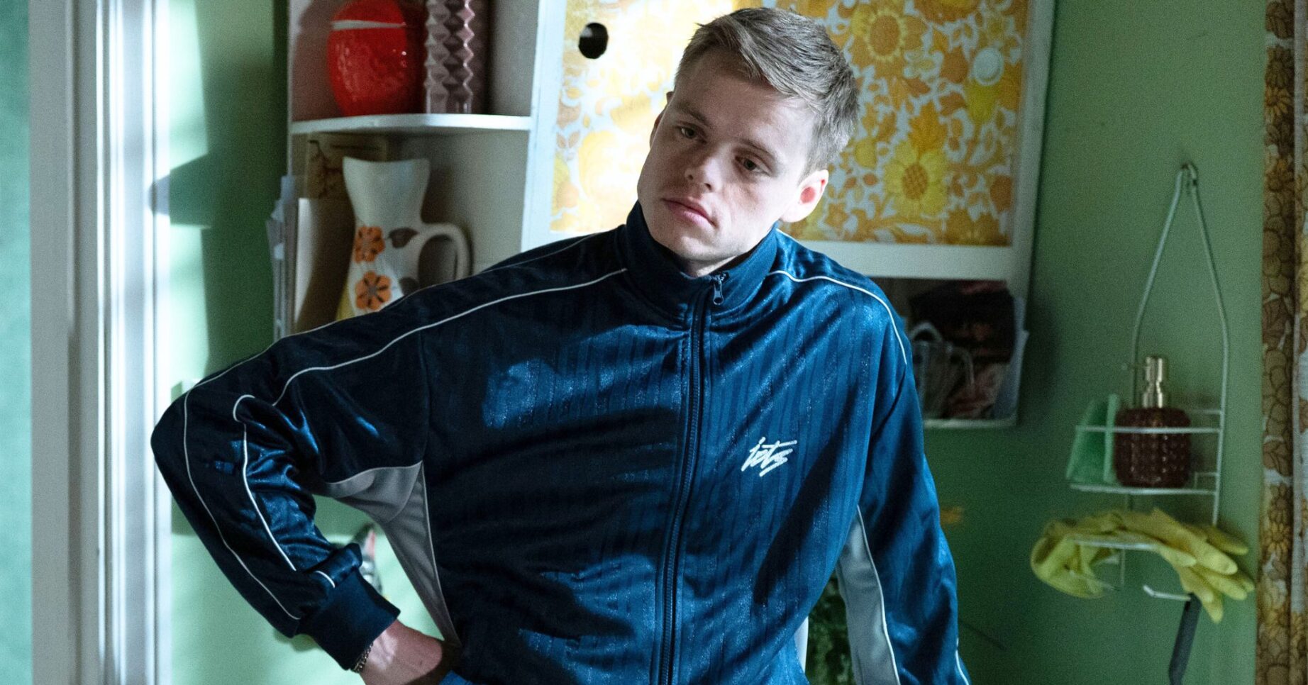 Oscar in eastEnders standing with his hand on his hip