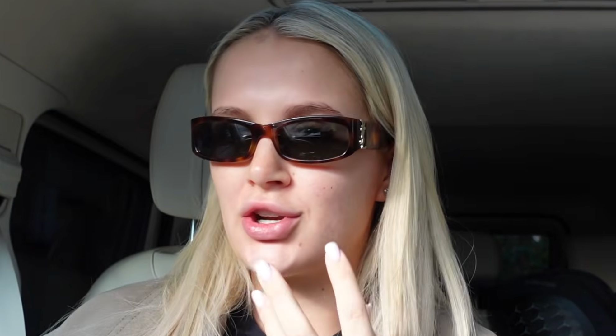 Molly-Mae Hague in her recent vlog wearing sunglasses and gesturing to her lips