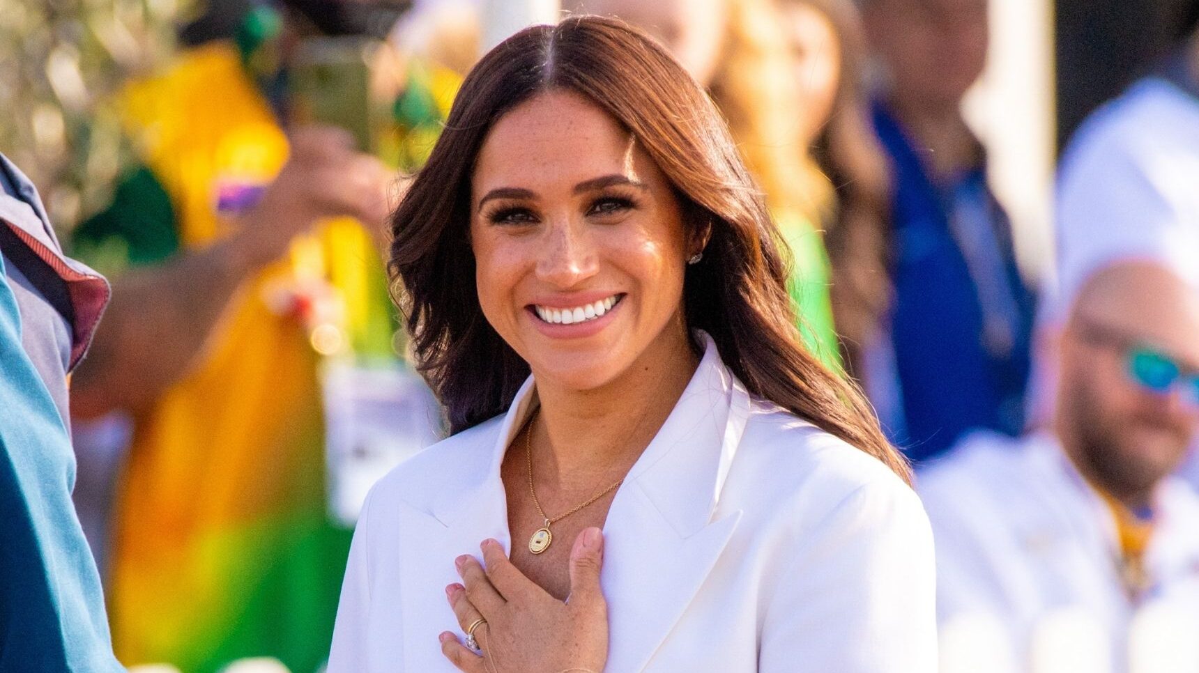 Meghan Markle smiling with her hand on her chest
