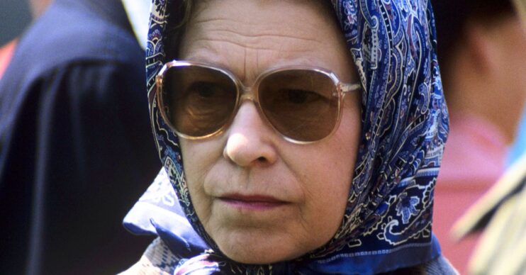 Queen Elizabeth wear sunglasses and a headscarf, with a worried, frowning expression