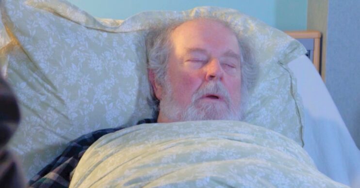 Julie sitting by Nigel's bed as he sleeps