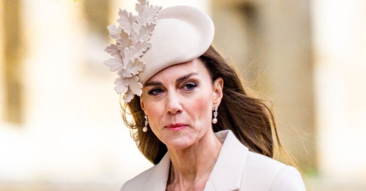 Princess Kate Middleton wearing a cream, floral hat with a serious expression