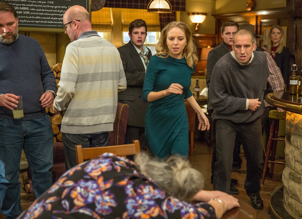 Lisa Dingle passed out on a table as Belle and Sam run to her in Emmerdale