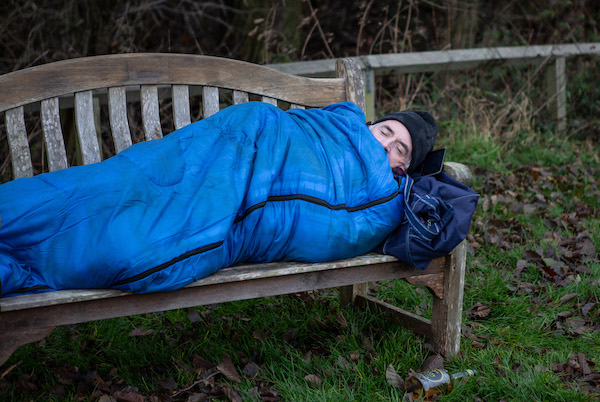 Bob sleeps on a bench wrapped in a blue sleeping bag in Emmerdale