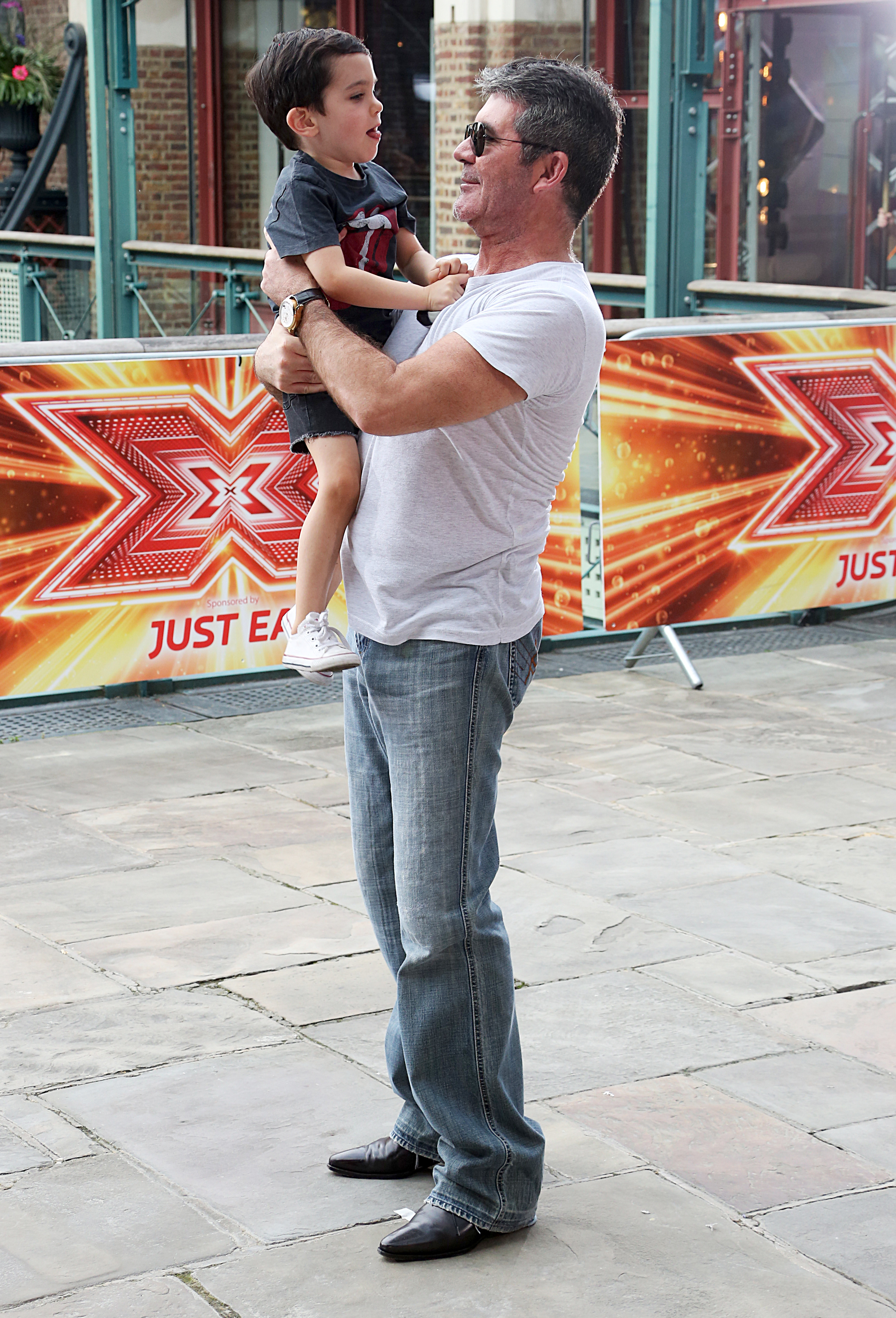Simon Cowell holding his son Eric in his arms