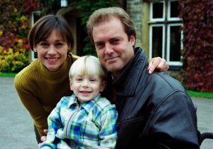 Zoe Tate, Chris Tate and Joe Tate smile outside Home Farm in Emmerdale