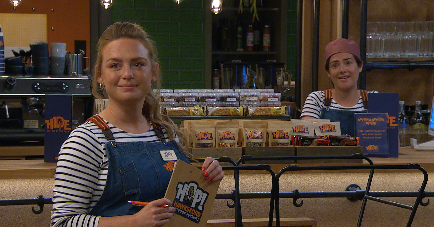Amy Wyatt in Emmerdale works in the HOP and smiles with her friend Victoria